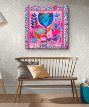 Vibrant boho-style canvas art with a whimsical floral pattern in bold shades of pink, blue, yellow, and orange.  The folk-inspired design features blooming flowers, leaves, and a small bird framed by a floral border, perfect for brightening eclectic or artistic home décor.