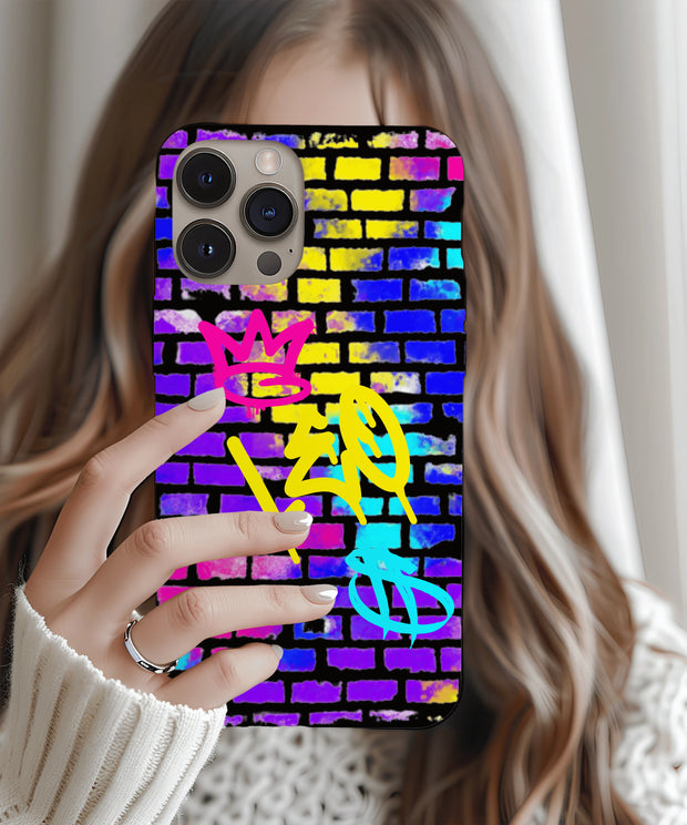 A bold phone case featuring vibrant graffiti-style “LEO” lettering in yellow, with a pink crown and teal symbol on a colorful brick wall background in neon blue, purple, and yellow tones.