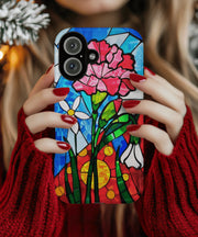 A vibrant phone case featuring January’s birth month flower — the pink carnation — in a stained glass mosaic design with white blooms, green leaves, and a radiant red and yellow sun background.