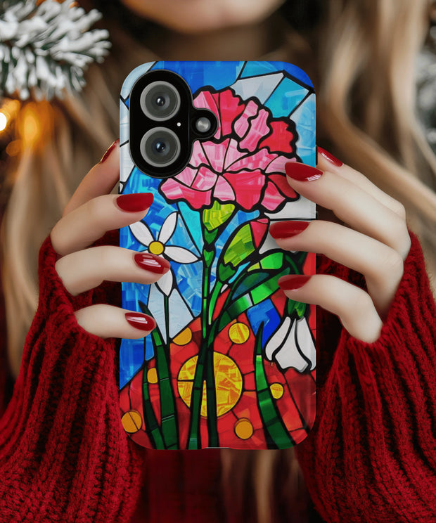 A vibrant phone case featuring January’s birth month flower — the pink carnation — in a stained glass mosaic design with white blooms, green leaves, and a radiant red and yellow sun background.