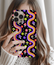 Colorful retro phone case featuring rainbow wavy lines, smiley face mushrooms, and bright flowers on a black background. Funky 70s-inspired psychedelic design with pink, purple, yellow, and green accents, perfect for groovy vintage lovers and bold aesthetics.
