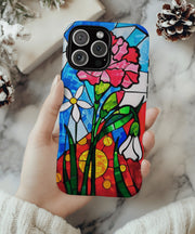 A vibrant phone case featuring January’s birth month flower — the pink carnation — in a stained glass mosaic design with white blooms, green leaves, and a radiant red and yellow sun background.