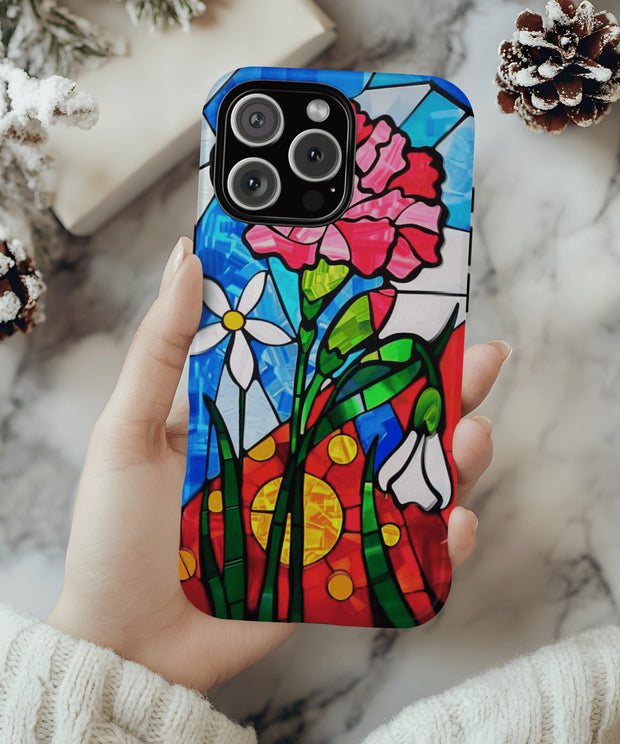 A vibrant phone case featuring January’s birth month flower — the pink carnation — in a stained glass mosaic design with white blooms, green leaves, and a radiant red and yellow sun background.