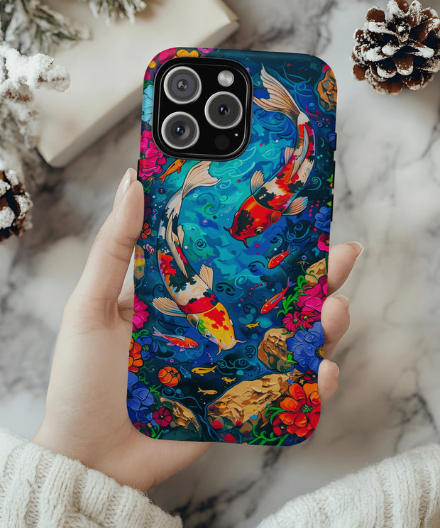 A vivid koi fish phone case featuring two colorful koi swimming in a bright blue pond surrounded by vibrant flowers, rocks, and swirling water patterns in a fantasy-inspired style.