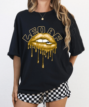 A black oversized t-shirt with bold text reading “LEO AF” above large metallic gold dripping lips, combining zodiac pride with a confident glam aesthetic, styled with a fierce and edgy look.