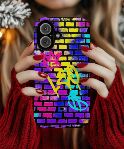 A colorful phone case with bold graffiti lettering that reads “LEO” in yellow spray-paint style on a vibrant brick wall background in shades of pink, blue, yellow, and purple, featuring a crown and zodiac-inspired street art motifs.