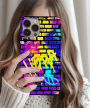 A vibrant phone case featuring the word “Libra” spray-painted in yellow graffiti over a colorful brick wall background, with pink and blue crown and zodiac symbols for a bold street art look.