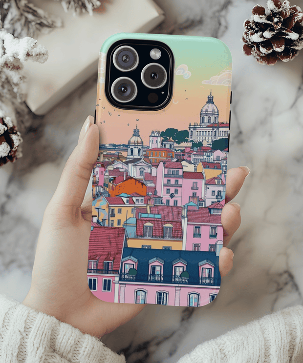 A pastel-toned phone case featuring a dreamy Lisbon cityscape with colorful rooftops, domed churches, and sunset skies in soft peach, mint, and pink hues, blending architecture and art in a whimsical travel aesthetic.