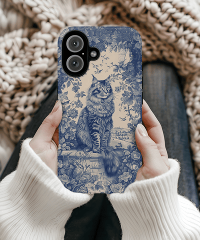 A tough phone case featuring an elegant navy blue toile de jouy illustration of a regal Maine Coon cat sitting among detailed floral patterns and vintage countryside scenery on a cream background.