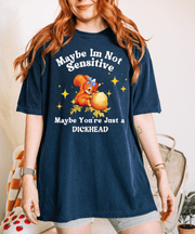 A navy oversized t-shirt featuring a vintage-style cartoon squirrel holding a giant acorn with sparkles around it. The shirt reads “Maybe I’m Not Sensitive, Maybe You’re Just a Dickhead” in playful white text.