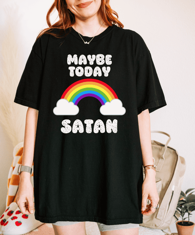 A black oversized t-shirt with white bubble letters reading “Maybe Today Satan,” featuring a bright rainbow and fluffy white clouds. The design combines dark humor with cheerful retro rainbow vibes for a playful, ironic twist.