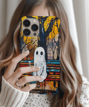 Phone case featuring a hand-painted ghost sitting alone on a park bench beneath dark trees and a vibrant yellow-orange autumn sky. The moody abstract background and emotional ghost design create a unique, artistic look perfect for fall or year-round gothic style lovers.
