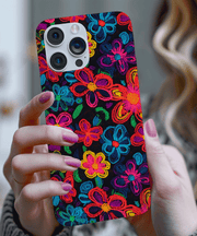 Phone case with a black background covered in vibrant neon embroidered-style flowers in pink, blue, yellow, orange, green, and purple. The colorful design mimics stitched thread for a textured, bold, and artistic look.