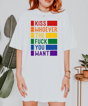 A white oversized t-shirt with bold rainbow block text reading “Kiss Whoever the F*ck You Want,” celebrating LGBTQ+ pride and freedom of love in a vibrant, unapologetic statement design.