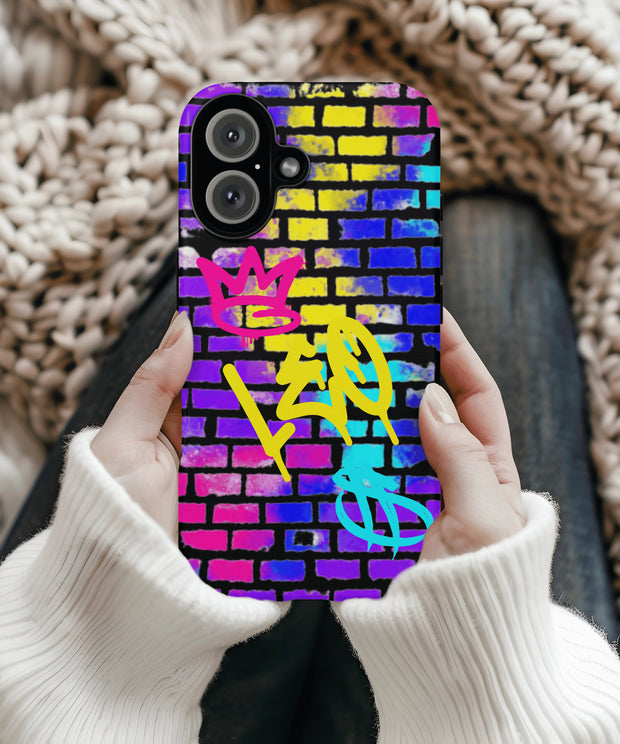 A colorful phone case with bold graffiti lettering that reads “LEO” in yellow spray-paint style on a vibrant brick wall background in shades of pink, blue, yellow, and purple, featuring a crown and zodiac-inspired street art motifs.